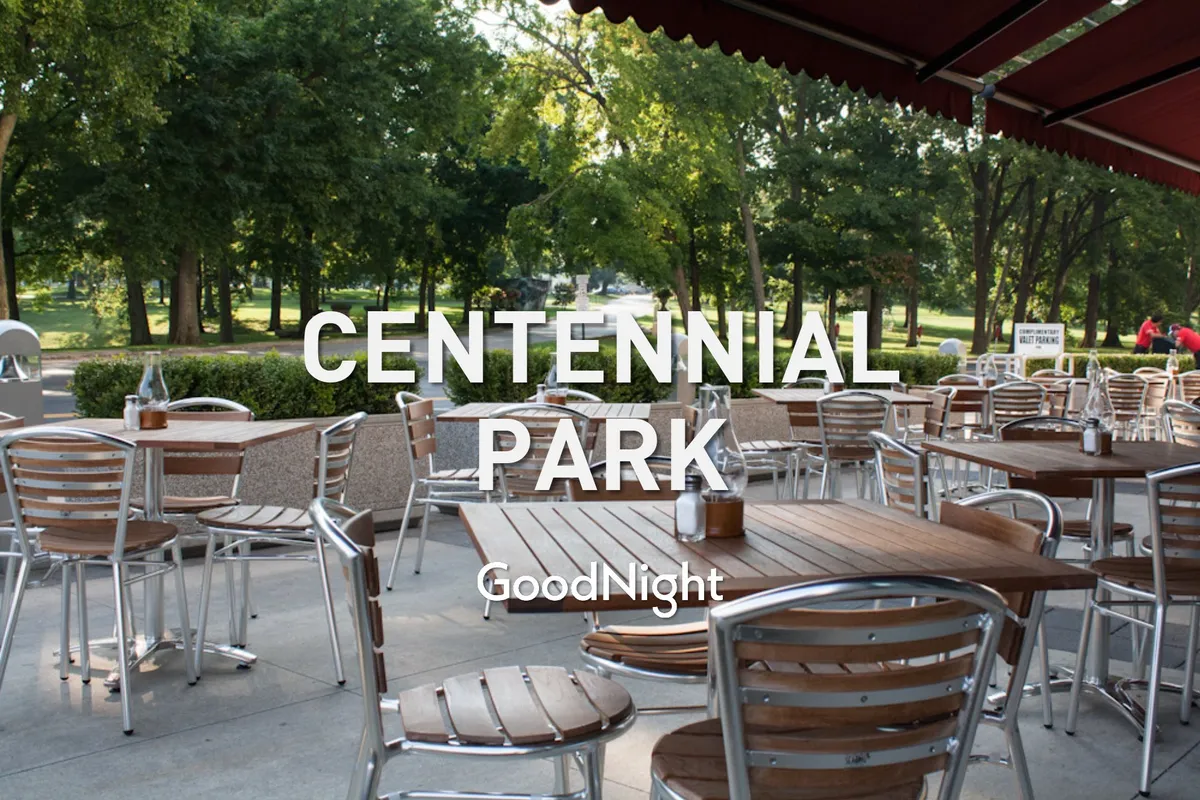 A cozy and stylish outdoor seating area with tables topped in wood, surrounded by lush greenery. The area is perfect for family meals, social gatherings, or enjoying a sunset together in a relaxed atmosphere.