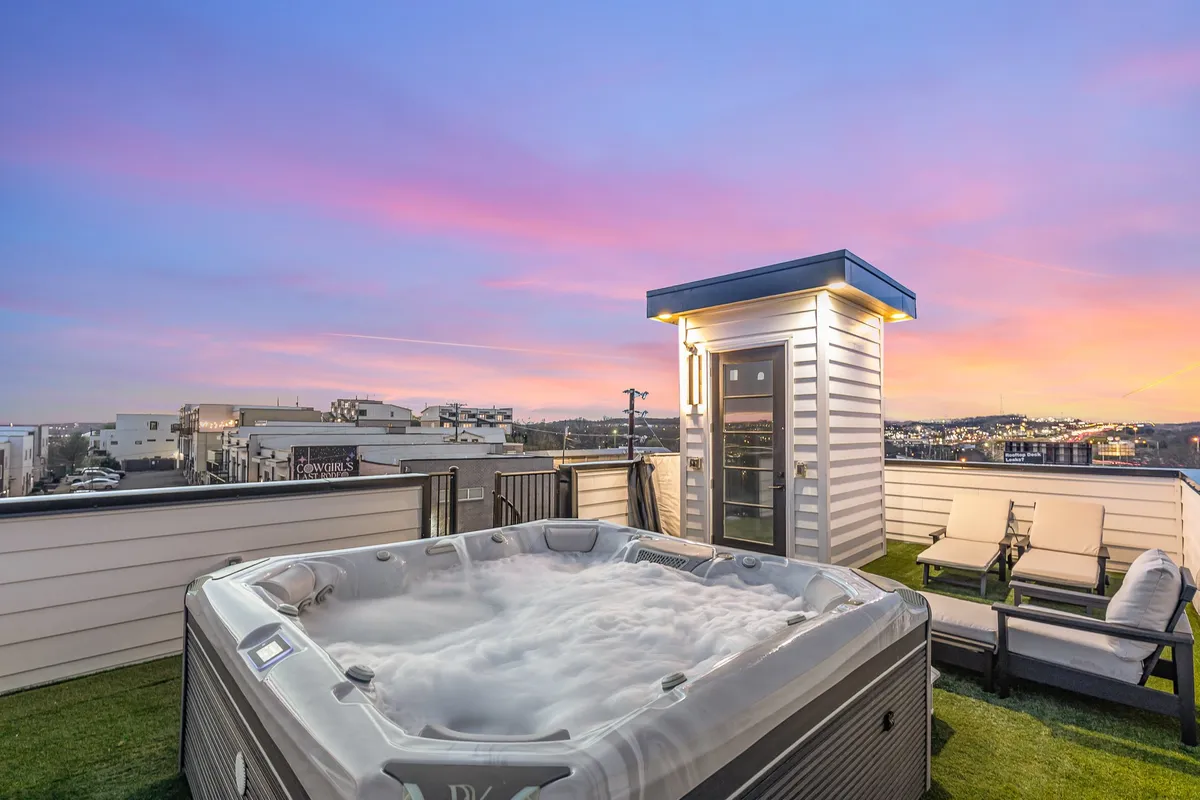 Another rooftop perspective showing a hot tub, outdoor lounge seating, and the skyline at sunset. The tranquil atmosphere highlights both relaxation and opportunities for intimate gatherings under the stars.